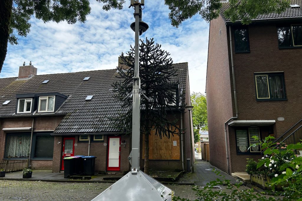 De gesloten woning, dichtgetimmerd en een mobiele camera voor de deur