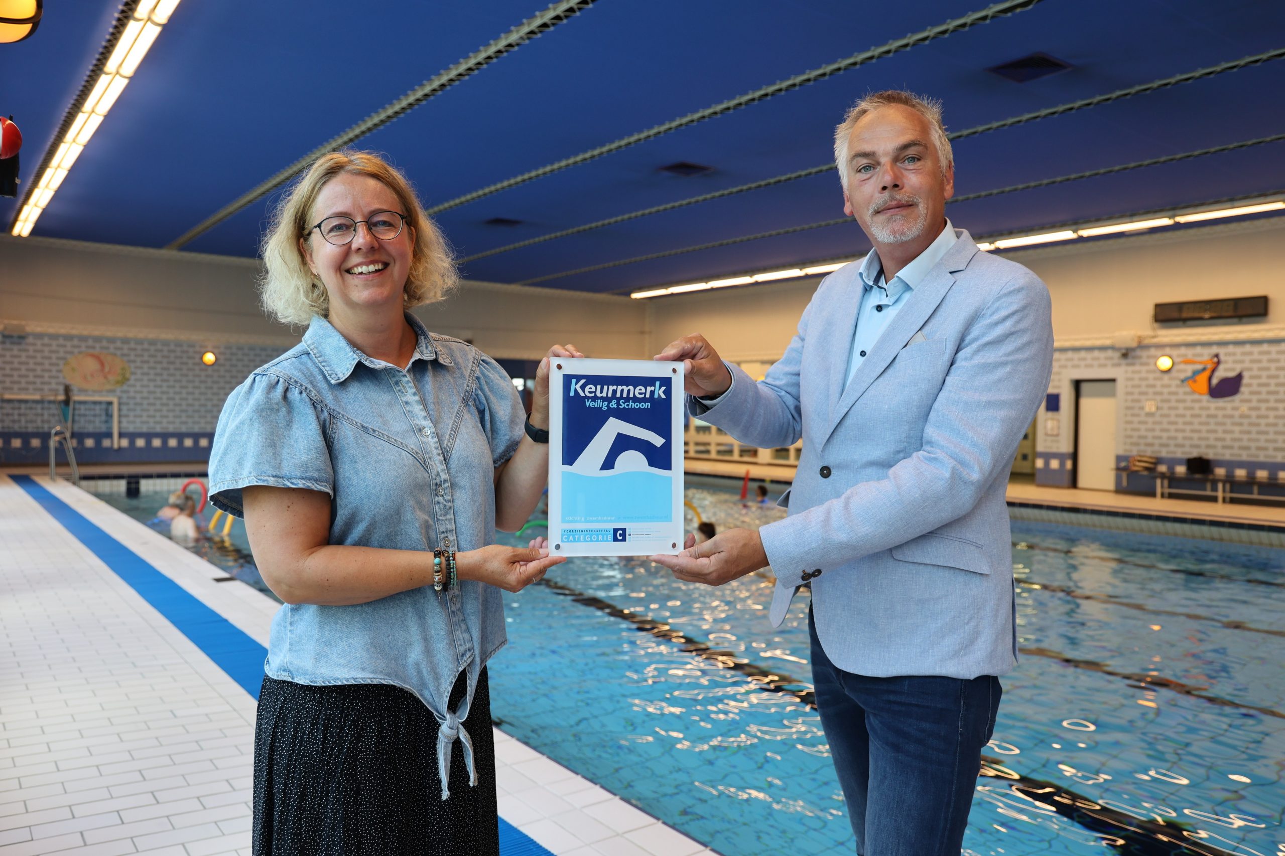 Teammanager Machteld Ustun overhandigt namens het gehele team vol trots het nieuwe bord voor de Dukdalf en vernieuwde certificaat aan wethouder Daan van Orselen (sport).